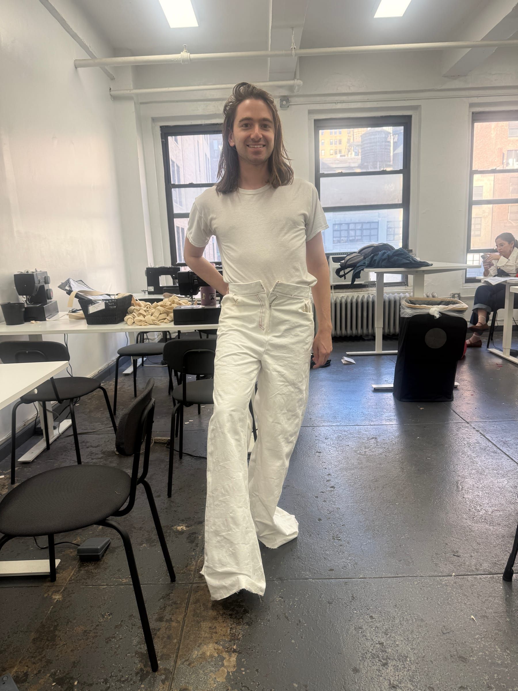 Andre in a white T-shirt and wide white trousers in a design studio