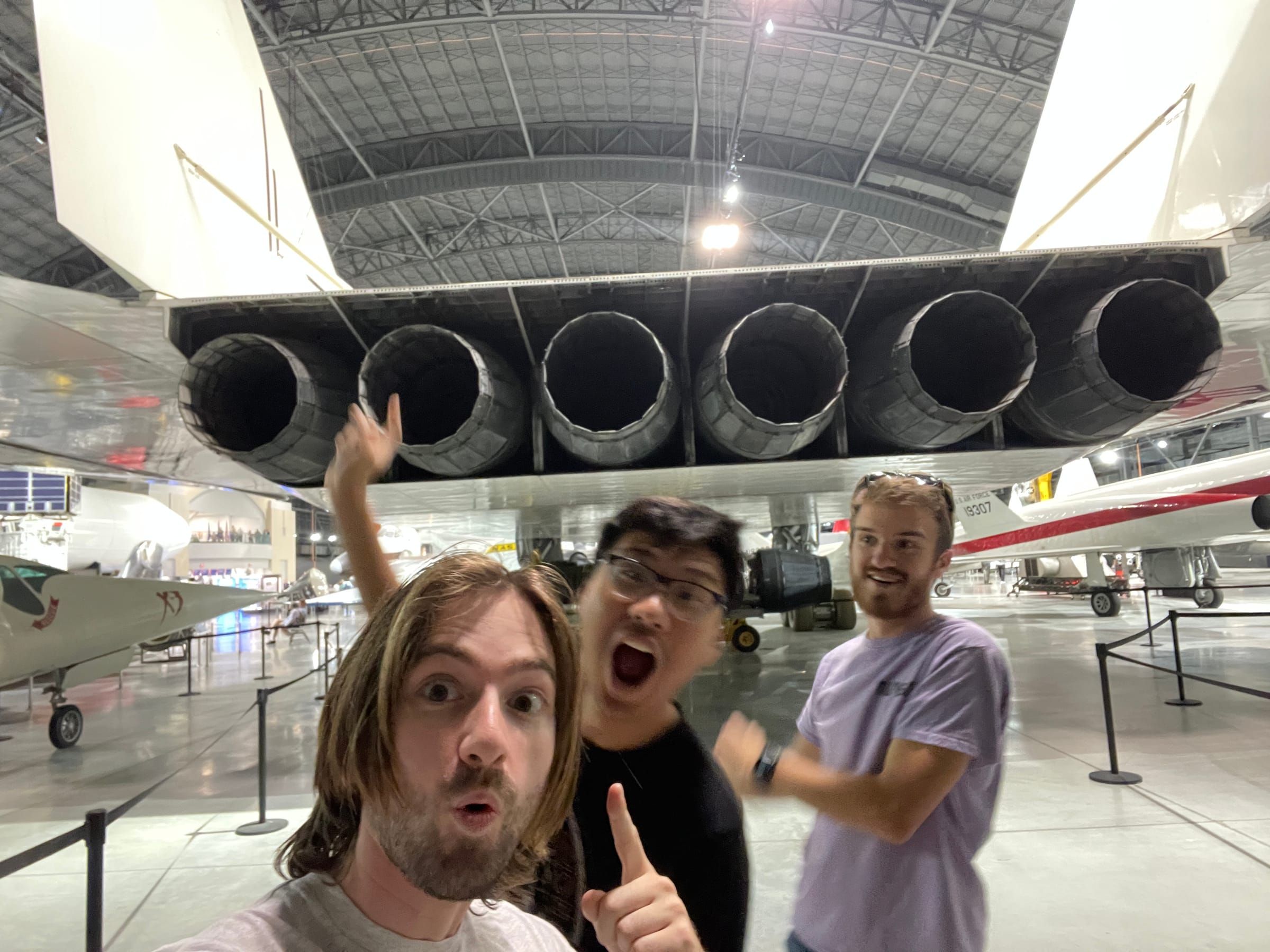 Three friends posing under the engines of a huge aircraft